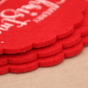 Detail of red felt Christmas coasters with white Merry text and scalloped laser-cut edges