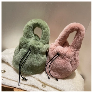 Detail view of plush sage green and soft pink drawstring bucket bags with furry texture