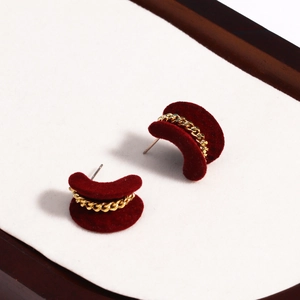 Close-up of red velvet C-shaped earrings with gold chain link detail on white background