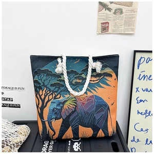Close-up of artistic elephant embroidery on a black canvas tote with cotton rope handles