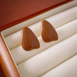 Close-up of vintage brown glazed teardrop earrings on a beige velvet jewelry box