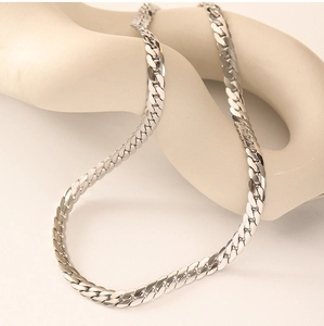 Macro shot of silver Cuban chain necklace on a minimalist display stand with high polish finish