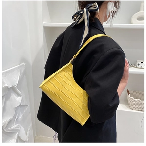 Close-up of bright yellow crocodile pattern underarm bag on a black blazer