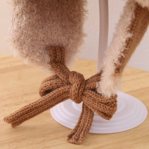 Detalle de gorro de invierno con forro beige y cordón de punto marrón con lazo decorativo