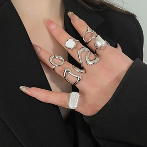 Detail shot of a six-piece silver metal ring set featuring irregular pearls on a hand