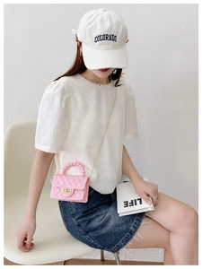 Pink quilted jelly bag with pearl handle shown on model wearing white top and denim skirt