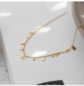 Detailed view of elegant gold thin chain necklace with solid water drop pendants