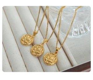 Detailed view of three gold vintage floral pendant necklaces in a jewelry box