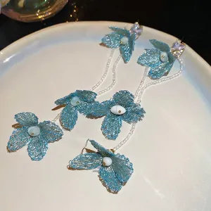 Floral tassel earrings with blue fabric petals, crystals, and long white bead strands