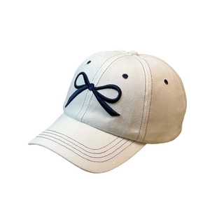 White baseball cap with navy blue bow embroidery and wide brim for sun protection