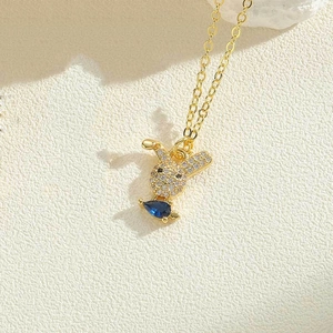 Macro detail of a golden rabbit pendant necklace with white zircons and a blue gemstone