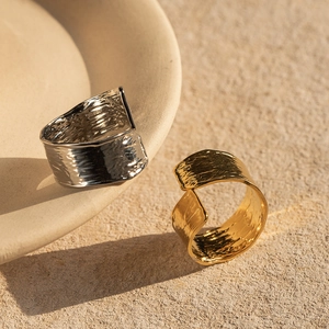 Gros plan de bagues martelées en or 18 carats et argent sur une surface en pierre