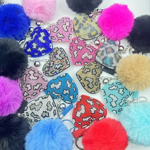 Detail showing various leopard heart keychains with rhinestones and fluffy plush balls