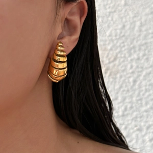 Exaggerated golden spiral hoop earrings in hollowed stainless steel on female model