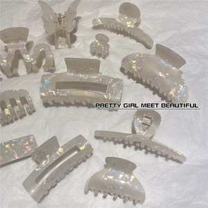 Detailed flat lay of iridescent acetate hair claws in various sizes on white textured paper
