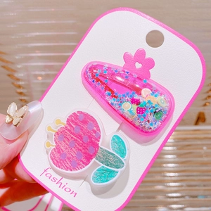Detail of pink hair clips featuring sequins, fruit slices, and a floral design on a card