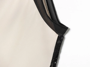 Detailansicht von cremefarbenem Satinstoff mit schwarzer Spitze und feiner Kante