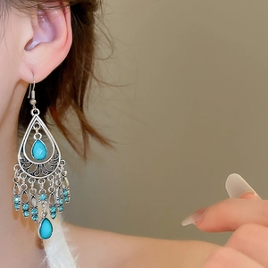 Detailed view of bohemian teardrop earrings with turquoise stones and blue tassels