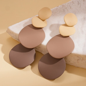 Detailed view of matte gradient earrings in beige and brown on white marble background
