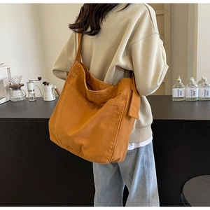 Detailed side view of a large caramel canvas tote bag with wide strap and side pockets