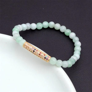 Close-up of light green jade beads with a micro-pave multicolored zircon gold tube charm