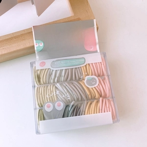 Macro detail of baby hair ties in pastel colors stored in a transparent Jewel Box case