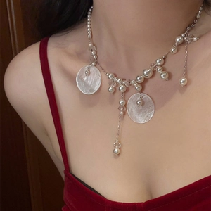 Detail of shell pearl tassel necklace on model highlighting elegant collarbone drop