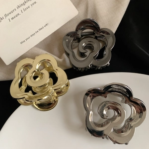 Three elegant rose-shaped metal hair claws in gold, silver, and gunmetal finishes
