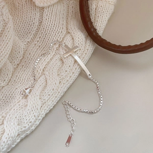 Detailed macro of S925 silver cross bracelet with box chain on knitted fabric