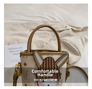 Close-up of beige leather mini bucket bag with cartoon rabbit and gold hardware