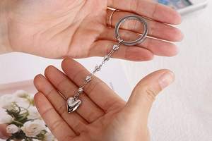 Detailed view of silver stainless steel keychain with heart links held in hand