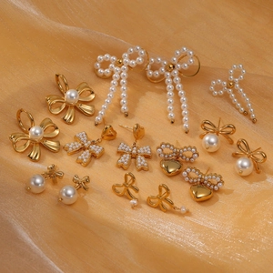 Detailed view of pearl bow earrings in gold finish on elegant golden silk fabric