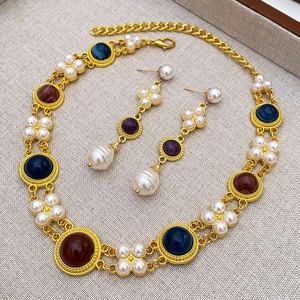 Vintage royal jewelry set featuring gold pearls and colorful gemstones on grey background