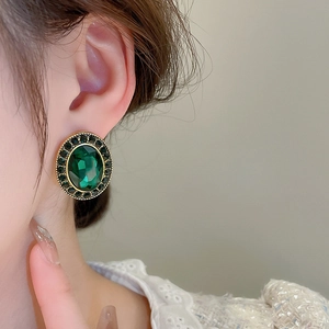 Détail macro de boucles d'oreilles ovales vert émeraude avec accents en métal doré