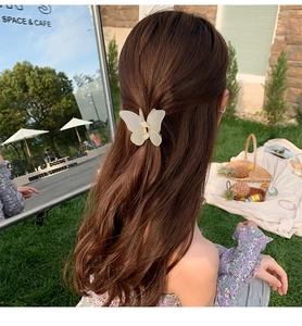 Close-up of a matte butterfly hair claw clip shown on a woman half-up hairstyle