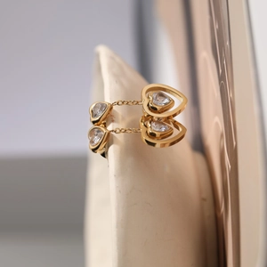 Detailed macro view of gold-plated double heart stud earrings with sparkling crystals