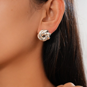 Close-up of a model wearing a silver knot stud earring with a polished metallic finish