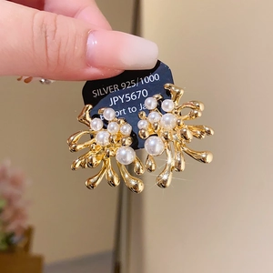 Macro shot of gold floral earrings with pearls and 925 silver needles on a card