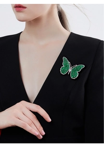 Macro detail of luxury butterfly brooch with green gems and zircons on black blazer
