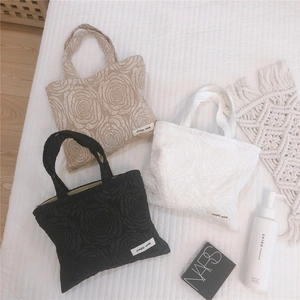 Detail of three rose-textured mini tote bags in beige, white and black with 3D floral pattern