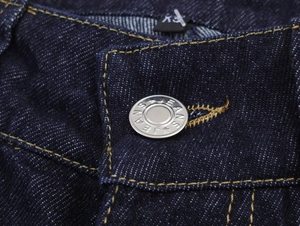 Détail du bouton argenté avec texte Jeans et étiquette XXL sur un pantalon en jean bleu