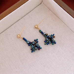Gros plan de boucles d'oreilles en perles irisées avec tiges dorées sur plateau beige