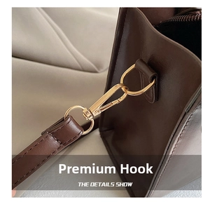 Détail d'un sac à main en cuir marron foncé avec fermoir mousqueton doré et bandoulière