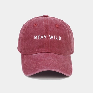 Detail of burgundy washed cotton baseball cap featuring Stay Wild white embroidery texture