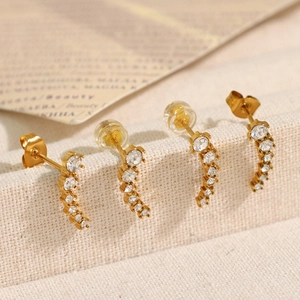 Elegant gold crescent zircon stud earrings set on minimalist textured fabric background
