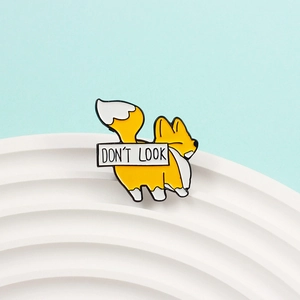 Detail of cute yellow fox enamel pin featuring Don't Look text on blue background
