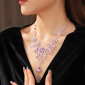 Close-up of vintage floral necklace with purple crystal teardrop on black velvet