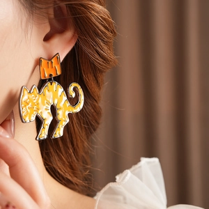 Detail showing the orange enamel cat earring with crown design worn on a model's ear