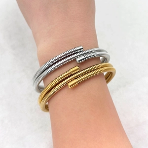 Detail of layered gold and silver spring coil bracelets worn on the wrist for a chic look