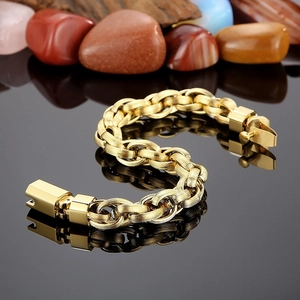 Close-up of golden O-chain bracelet with textured links on black reflective surface